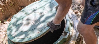 The man opens the sewer hatch. Installation and maintenance of septic tanks.